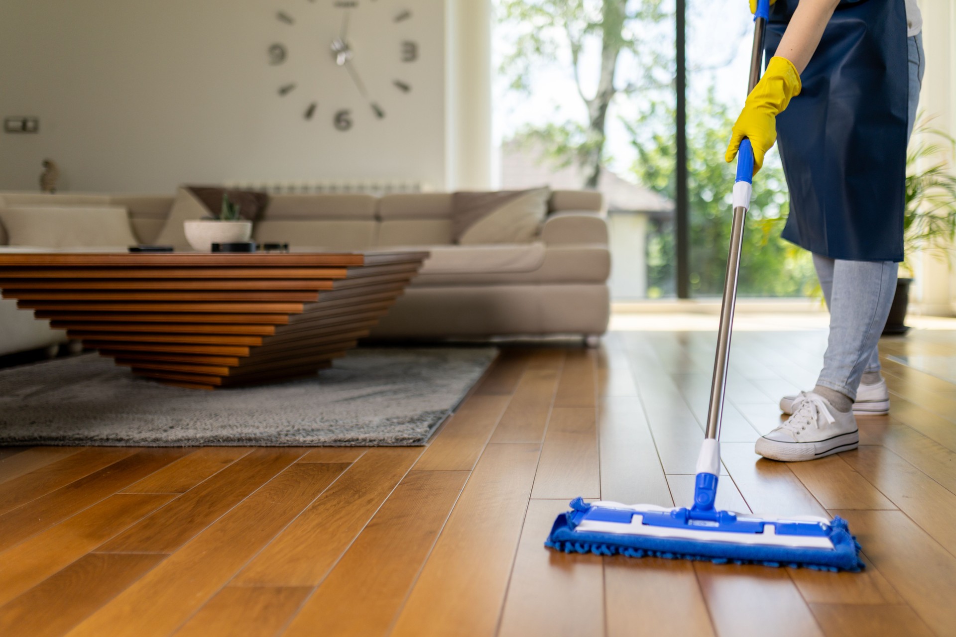 Cleaning hardwood floors in modern living room with effective cleaning tool during daytime